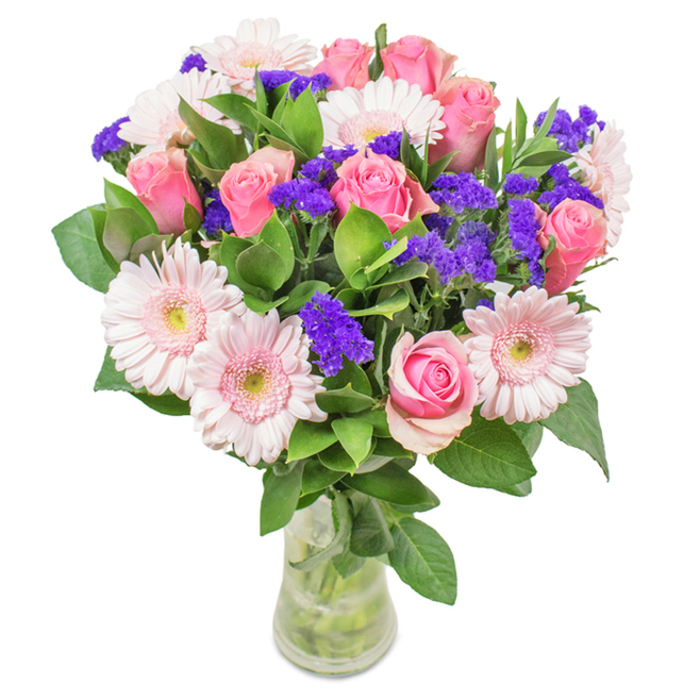 A sophisticated and lively bouquet, arranged in a transparent glass vase and set against an immaculately white backdrop, captures the essence of floral artistry for Rotherhithe homes and offices. The arrangement showcases a striking core of seven to nine pink roses-some tightly furled, others just beginning to unfold-each displaying the renowned spiral formation emblematic of expert floristry. These romantic roses are interspersed with five to seven pale pink gerbera daisies, whose large, cheerful, round blooms and nearly white hearts lend a soft radiance. Vivid purple clusters of statice or limonium thread through the composition, creating an arresting textural and chromatic contrast, while a lush base of deep green foliage-reminiscent of local parks-injects vitality and abundance. Subtle reflections on the vase surface hint at soft indoor light, enhancing each flower's colour nuance. The bouquet, with stems submerged and visible in clear water, suggests proprietary freshness and readiness for same-day delivery from Flower Delivery Rotherhithe to addresses from Lower Road to Greenland Dock. As a gift, it communicates celebration, gratitude, or support-its elegant presence and gentle fragrance making it ideal for occasions such as birthdays, anniversaries, or gentle everyday 'thinking of you' moments, always marked by a distinctive local touch.